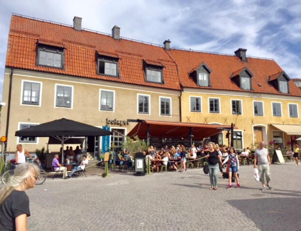 un grupo de personas caminando delante de un edificio en Stora Torget - Visby Lägenhetshotell, en Visby