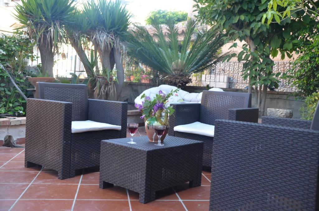 eine Terrasse mit Stühlen und einem Tisch mit einem Glas Wein in der Unterkunft Orion Accomodation in Tropea