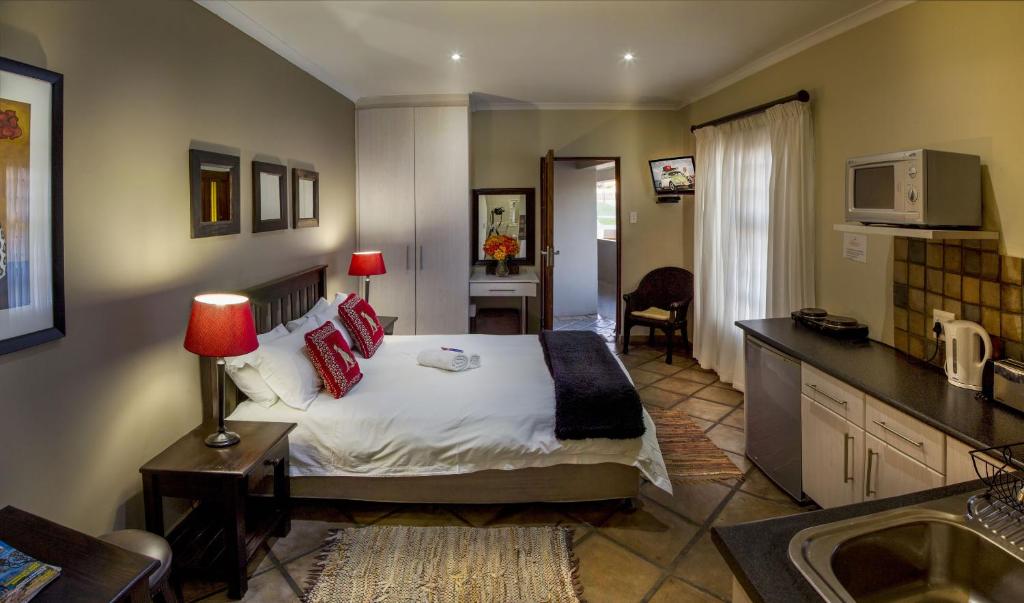 Lalapanzi Guest Lodge في بورت اليزابيث: غرفه فندقيه بسرير ومطبخ