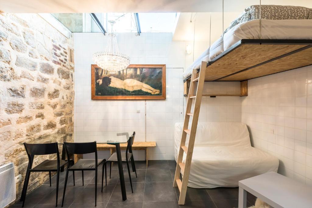 パリにあるAttractive 25 m2 in a central districtの二段ベッド、テーブル、椅子が備わる客室です。