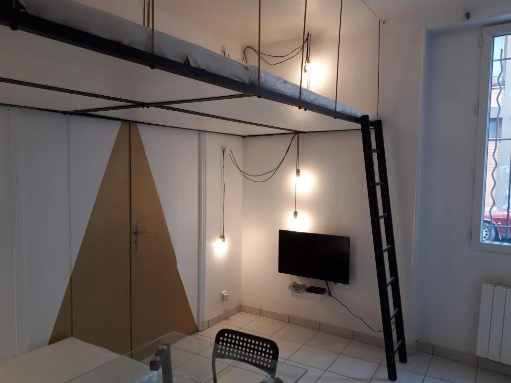 Cette chambre comprend un lit en mezzanine avec une télévision et une chaise. dans l'établissement Enjoyable 20m² MONTREUIL 5 minutes Paris, à Montreuil