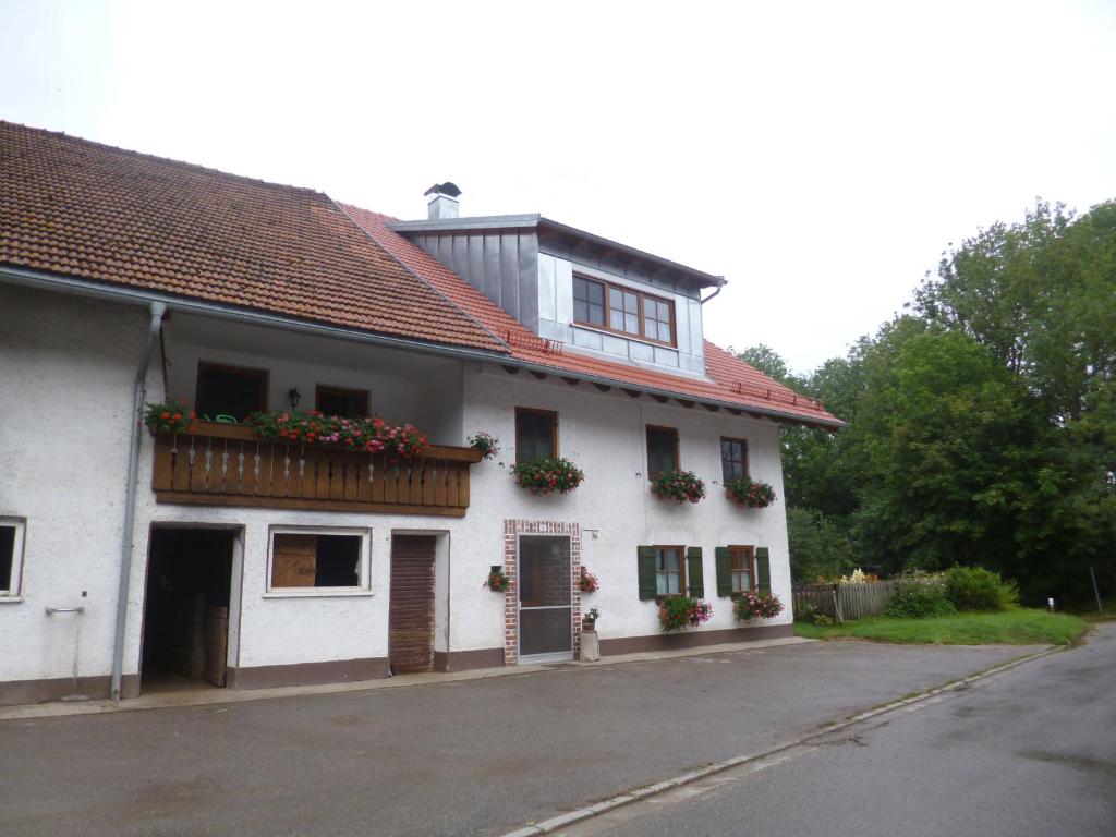 uma casa branca com caixas de flores nas janelas em Ferienwohnung auf dem Lechsberg em Fuchstal