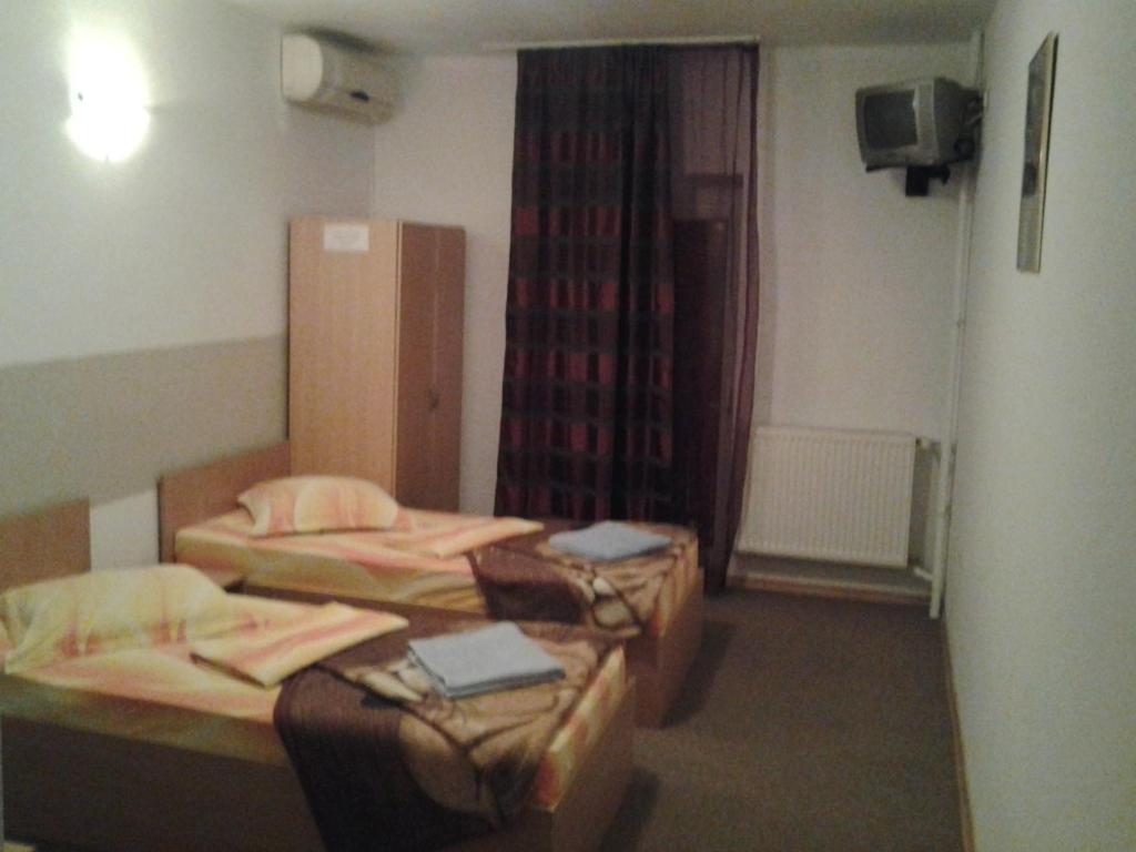 a hotel room with two beds and a television at Pensiunea Raffael in Otopeni