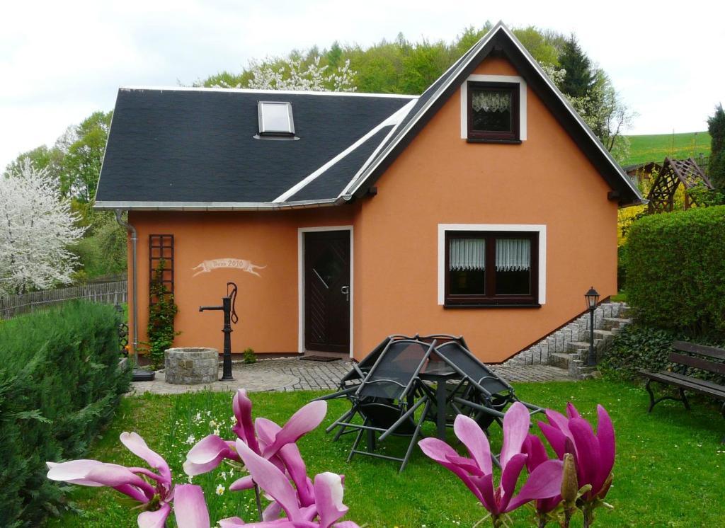 a small orange house with pink flowers in the yard at Ferienhaus Uda in Schwarzenberg