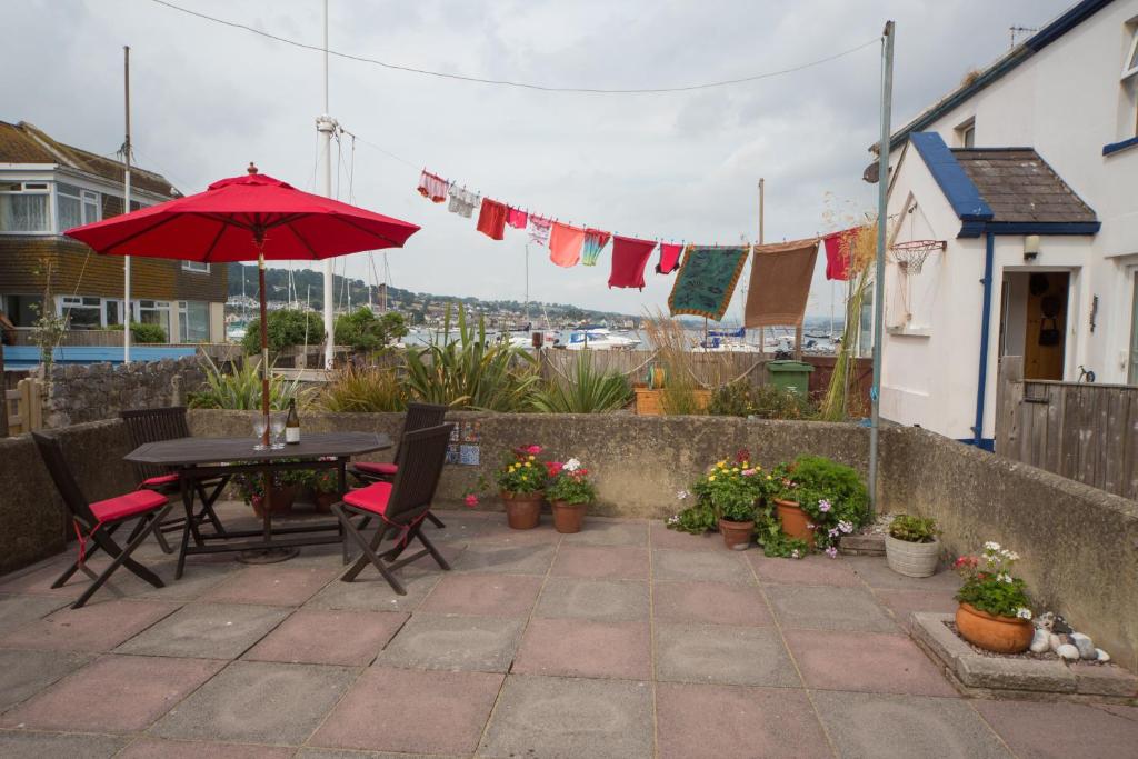 a patio with a table and chairs and an umbrella at Polly Cottage in Teignmouth