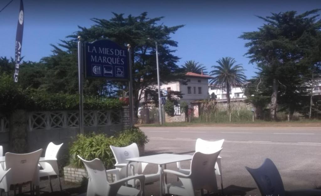 un tavolo con sedie e un cartello sul lato della strada di La Mies del Marqués a Santoña