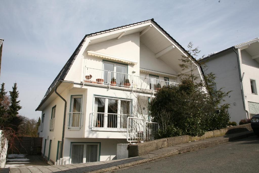 a white house with a balcony on a street at Apartmentvermietung Dortmund-Kirchhörde in Dortmund