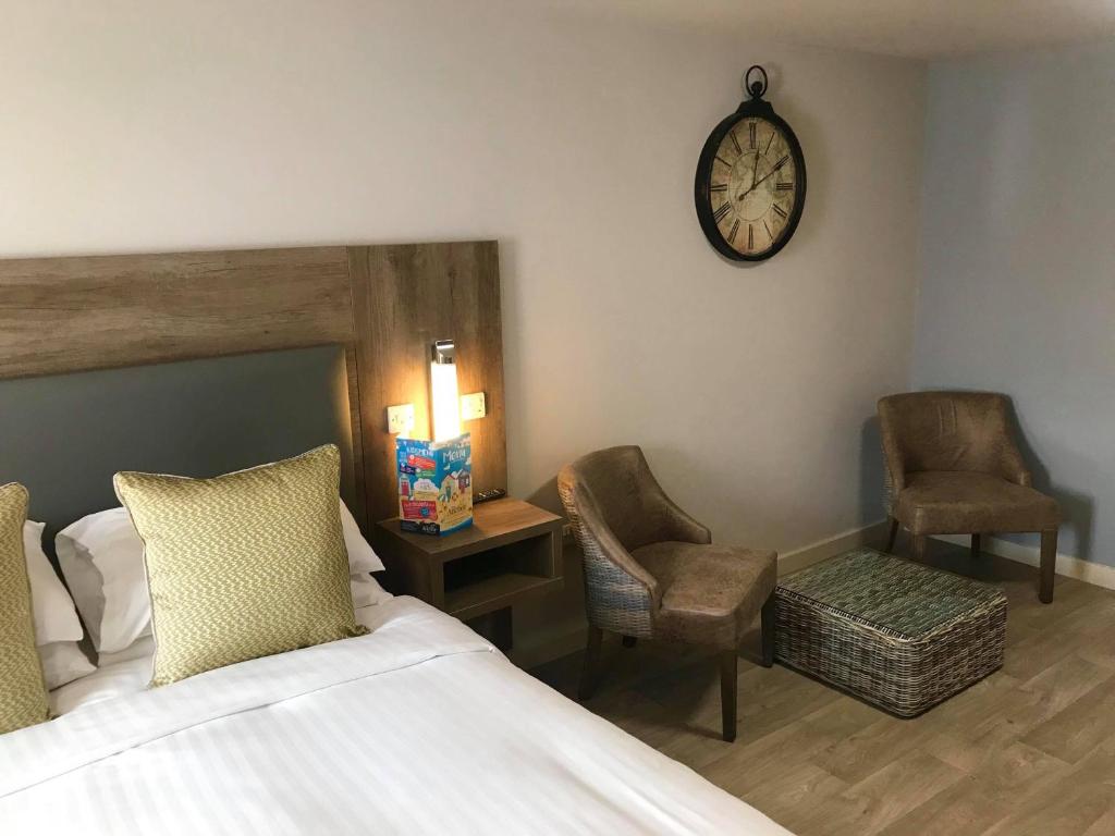 a bedroom with a bed and two chairs and a clock at The Anchor Hotel & Bars in Ingoldmells