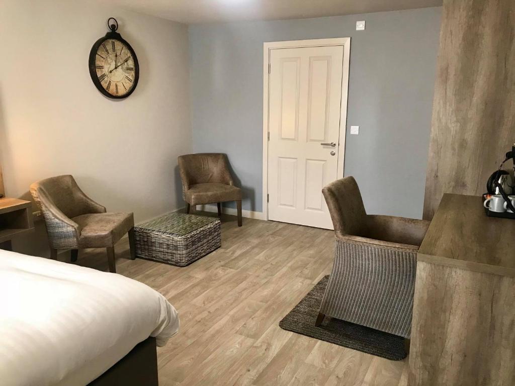 a bedroom with two chairs and a clock on the wall at The Anchor Hotel & Bars in Ingoldmells