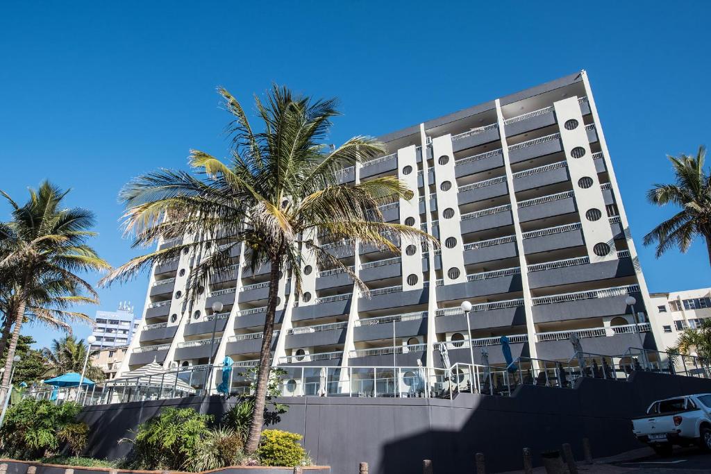 un grand bâtiment avec des palmiers devant lui dans l'établissement First Group Margate Sands, à Margate