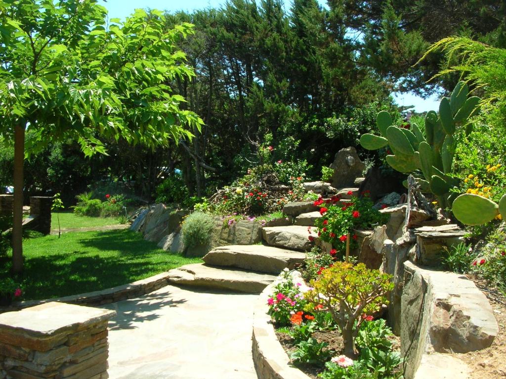un giardino con alcuni fiori, rocce e alberi di LOCALITA' LA PELOSA VIA PUNTA D'ELICE N° 9 a Stintino