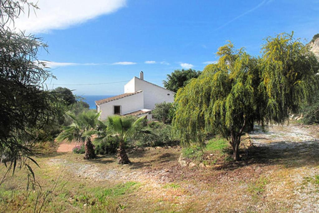 een wit huis bovenop een heuvel met bomen bij Cortijo la Venta in Nerja