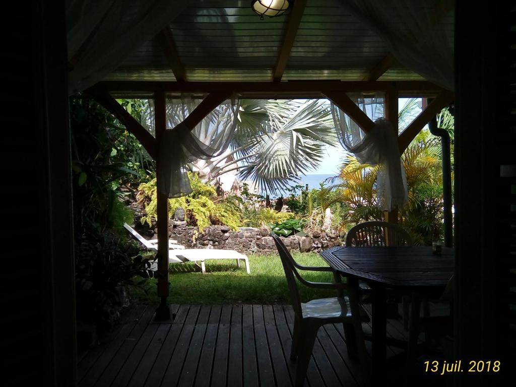 a porch with a table and chairs and a bench at La Villa Jasmin in Les Anses-dʼArlets