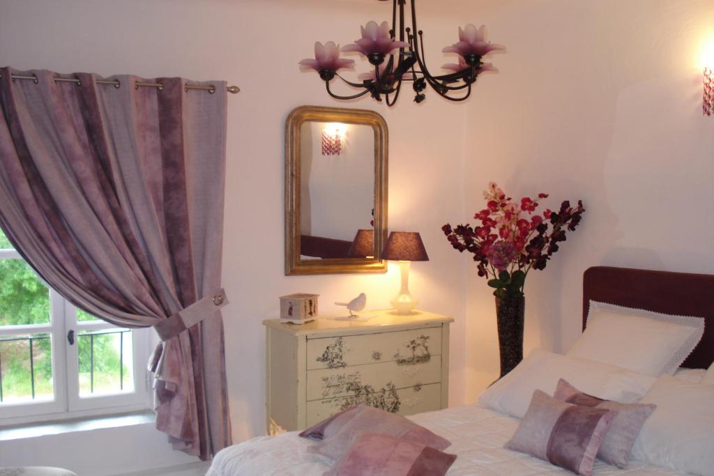 um quarto com uma cama e um espelho e um vaso de flores em Mas De La Coucourde em Paluds de Noves