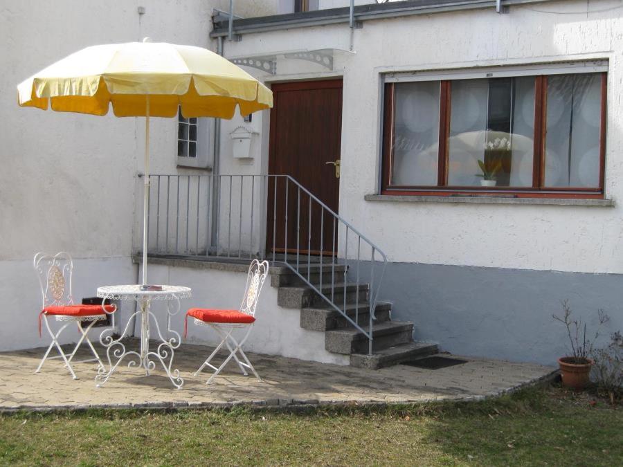 1-Zimmer-Apartment Heßdorf في هيسدورف: طاولة وكراسي ومظلة أمام المنزل