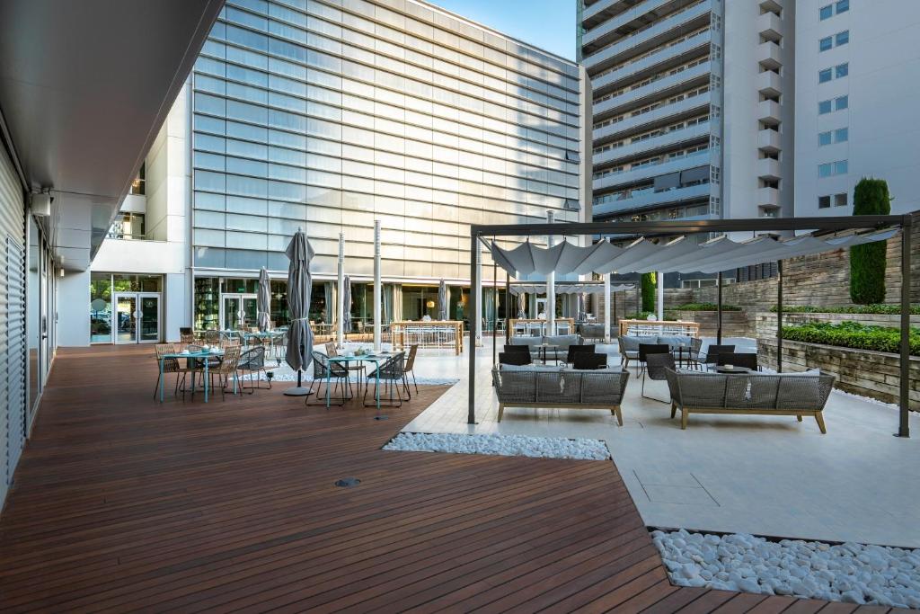 a deck with chairs and tables and a building at Vincci Maritimo in Barcelona