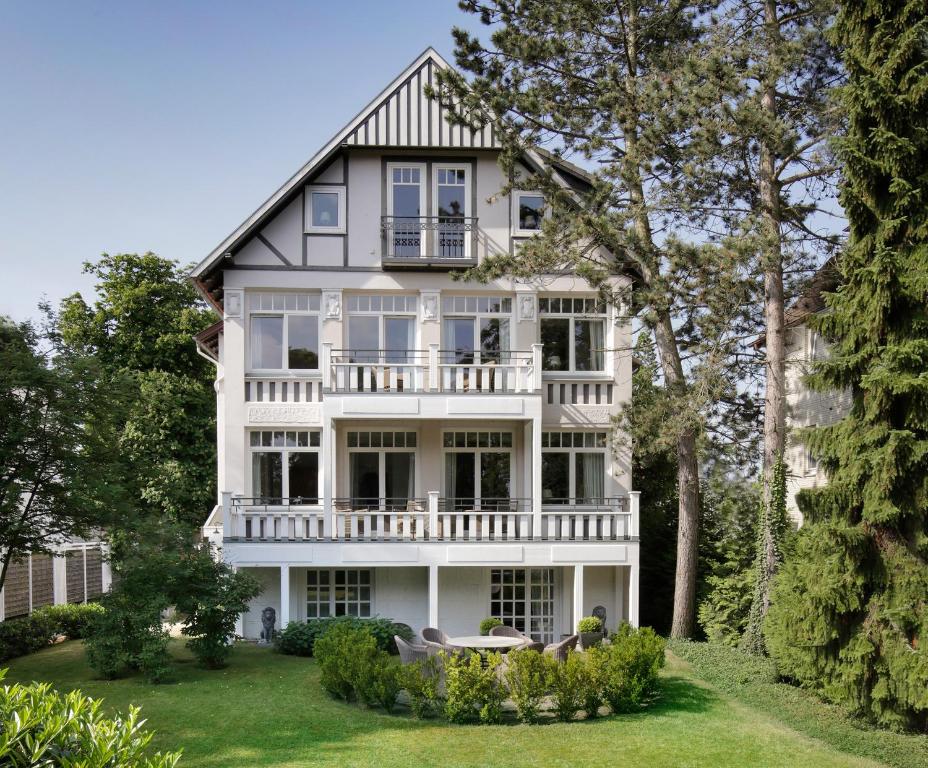 an exterior view of a white house with trees at Villa An Der See in Timmendorfer Strand