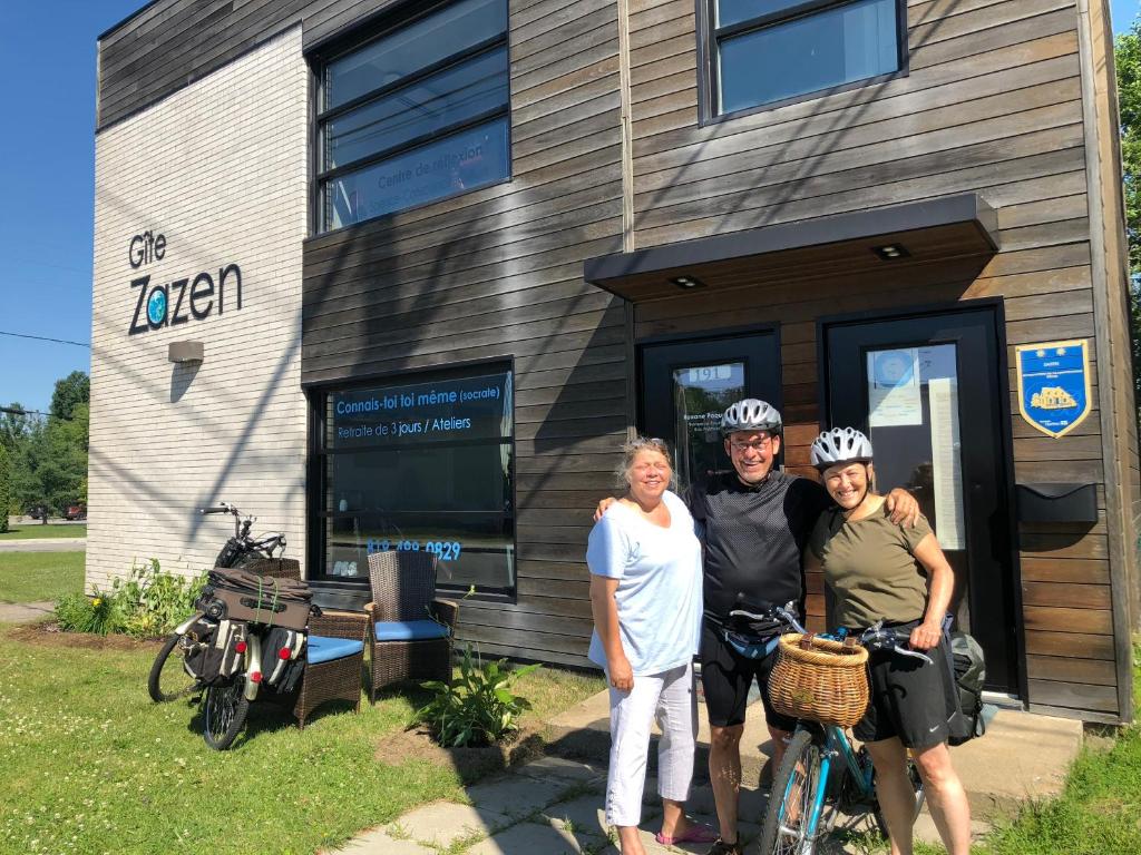 three people standing in front of a building with their bikes at Gîte Zazen in Mont-Laurier