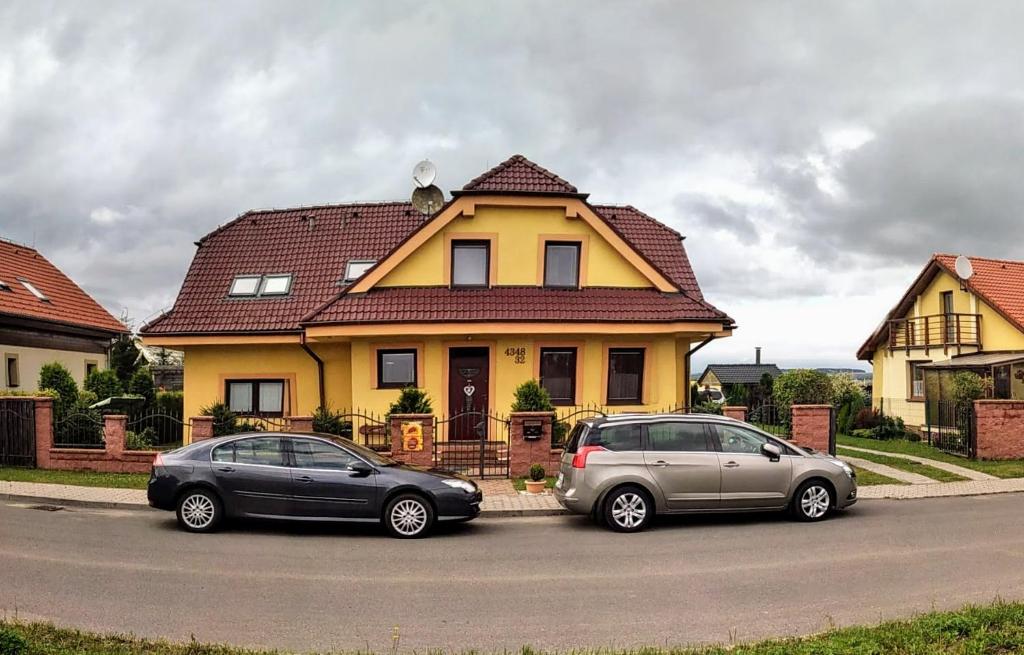 dos autos estacionados frente a una casa amarilla en Apartmán Slnečnica, en Poprad