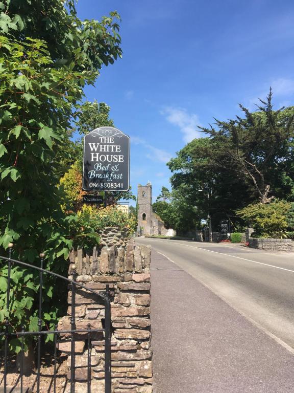 um sinal para uma casa branca na berma de uma estrada em The White House B & B em Kenmare