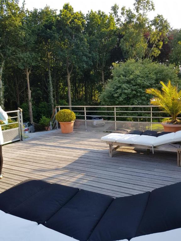 a deck with two beds and a fence and trees at La Canopée des Pins in Cléder