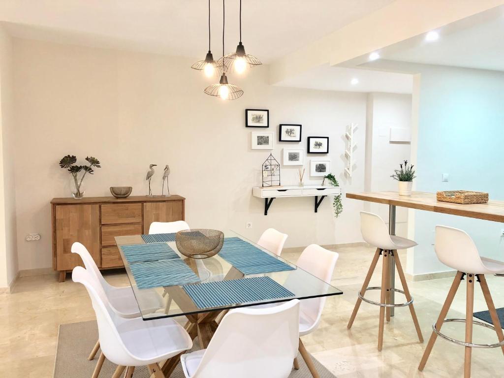 comedor con mesa de cristal y sillas blancas en Apartamento Guadalmina - Golf & Playa - Marbella, en Marbella