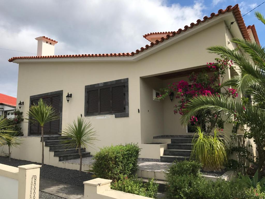 una casa blanca con plantas delante en Holiday House, São Roque do Pico, en Cais do Pico