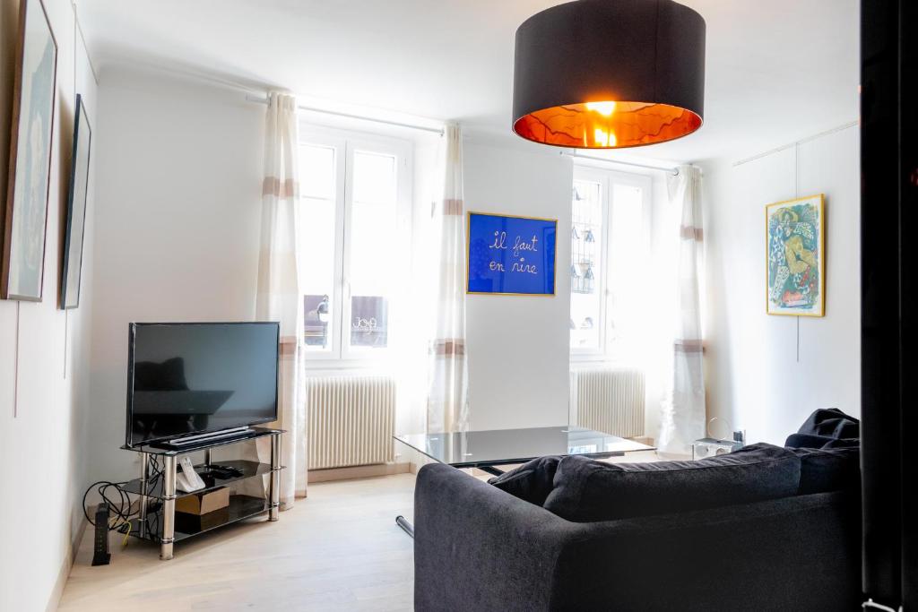 ein Wohnzimmer mit einem Sofa und einem TV in der Unterkunft Place du Pin in Nizza