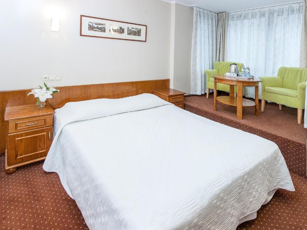 ein Hotelzimmer mit einem Bett und einem Tisch und Stühlen in der Unterkunft Willa Biala Lilia Old Town in Danzig