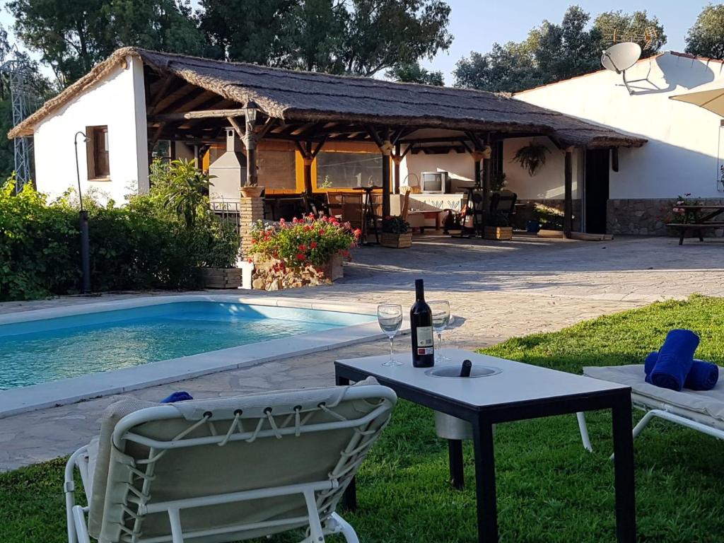 a table with a bottle of wine and two chairs next to a pool at Casa Rural Vega el Dorado in San Pablo