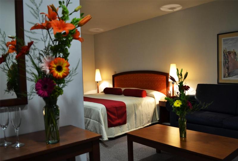 a hotel room with a bed and flowers in vases at Hotel Mediterraneo Sa De Cv in Tulancingo