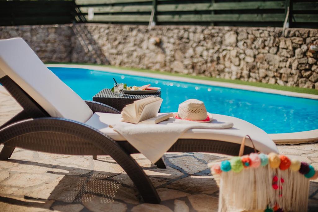 een tafel met een hoed en een boek naast een zwembad bij Kalpic Suites & Villa in Lozovac