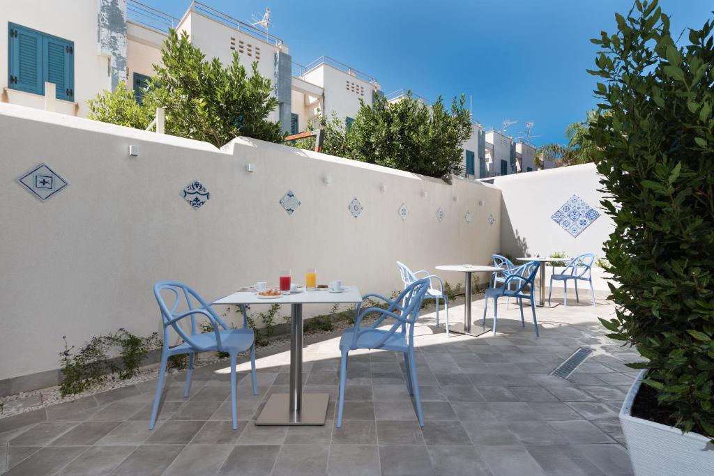 a patio with tables and chairs and a wall at Hermes Hotel in San Vito lo Capo