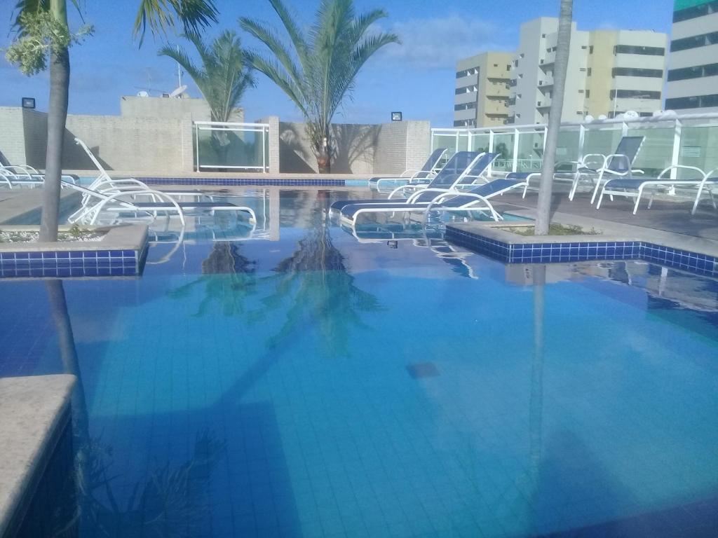 una gran piscina azul con sillas y palmeras en Beira Mar Praia Jatiúca, en Maceió