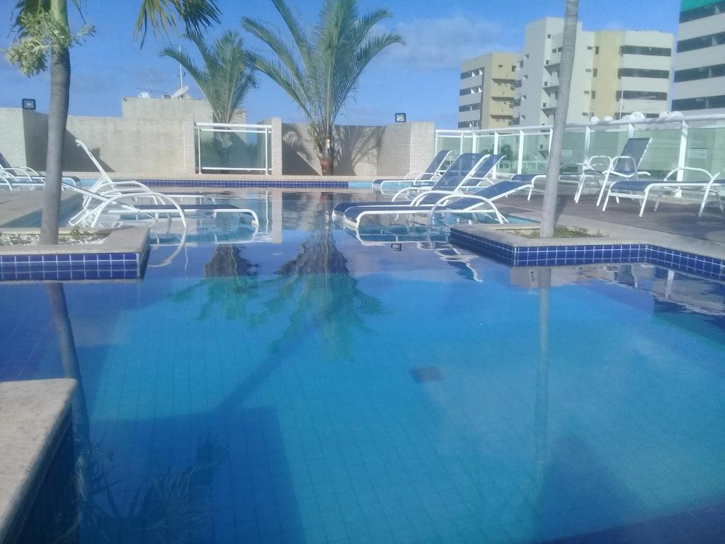 uma grande piscina azul com cadeiras e palmeiras em Beira Mar Praia Jatiúca em Maceió