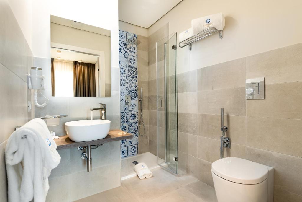 a bathroom with a sink and a toilet and a shower at Hermes Hotel in San Vito lo Capo