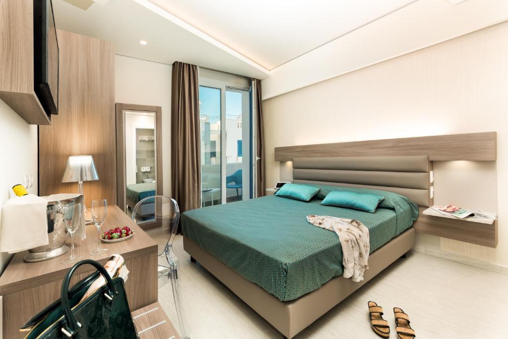 a bedroom with a bed and a table and a desk at Hermes Hotel in San Vito lo Capo