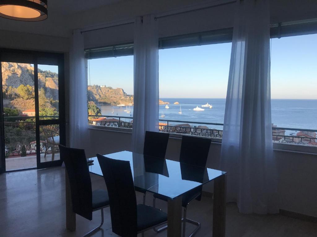 una sala da pranzo con tavolo e vista sull'oceano di Baia Taormina Apartment a Giardini Naxos