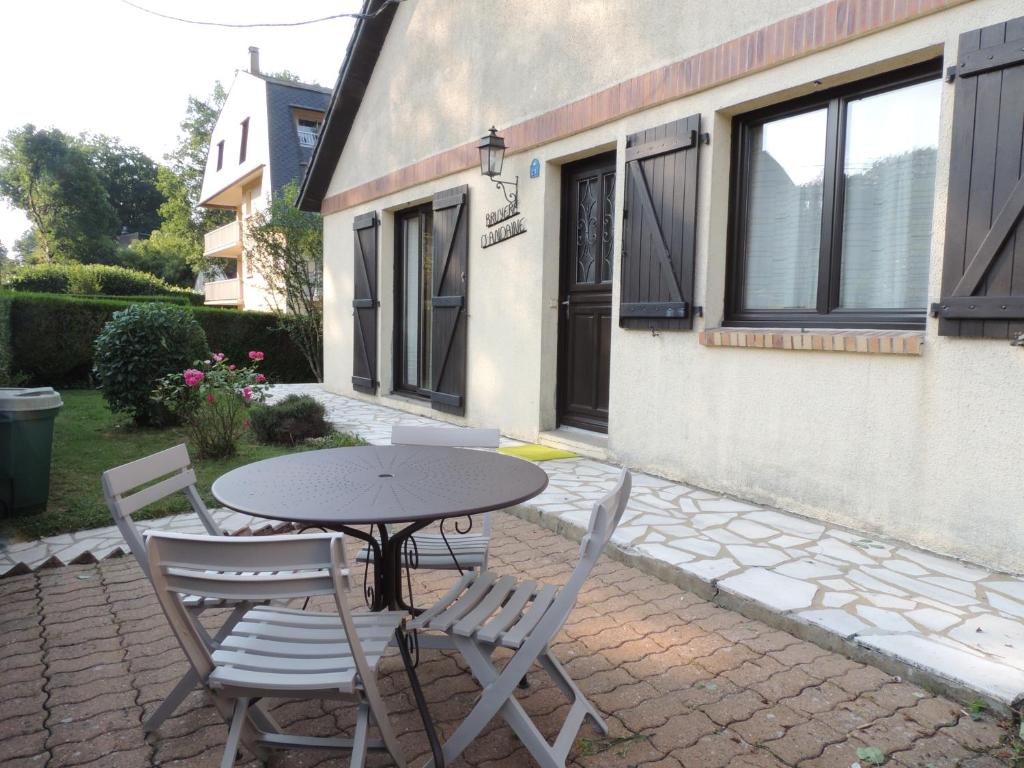 une terrasse avec une table et des chaises devant une maison dans l'établissement BRUYERE D'ANDAINE, à Bagnoles-de-l'Orne