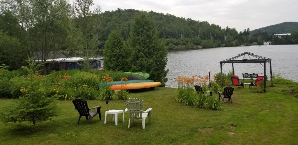 a group of chairs and a gazebo next to a lake at Auberge Aux Nuits de Rêve in Sainte-Agathe-des-Monts