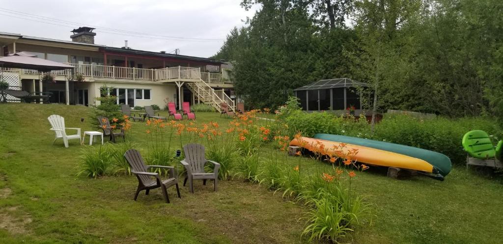 a garden with a boat and chairs and a house at Auberge Aux Nuits de Rêve in Sainte-Agathe-des-Monts