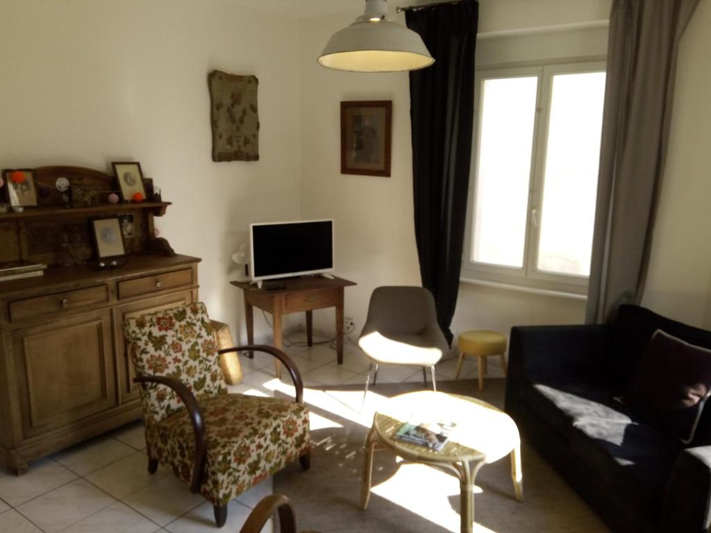 a living room with a couch and chairs and a tv at Slow Life House in Saint-Maurice-sous-les-Côtes