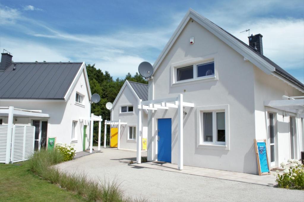 a white house with a blue door in a yard at Osada Rybacka in Kopalino