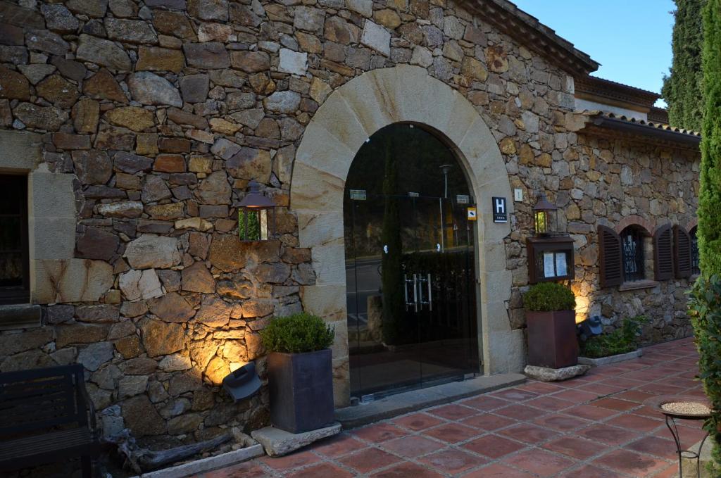 una entrada a un edificio de piedra con una pared de piedra en Hotel Galena Mas Comangau en Begur