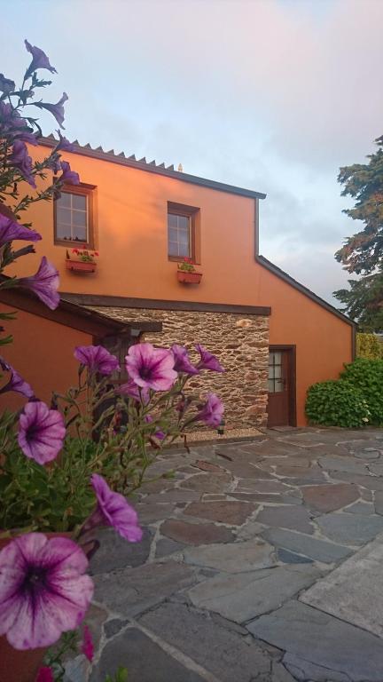 una casa con flores púrpuras delante de ella en Casa Dos Nenos, en San Martín