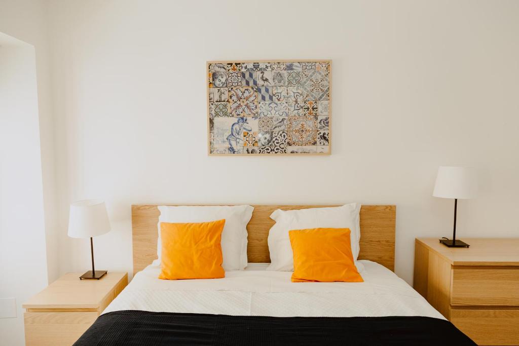 リスボンにあるA Casa do Jardim à Estrela Iのベッドルーム1室(オレンジ色の枕2つ、ベッド1台付)