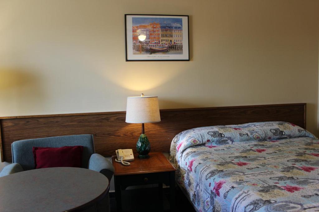 una camera d'albergo con letto e tavolo con lampada di Wheatland Motel a Vulcan