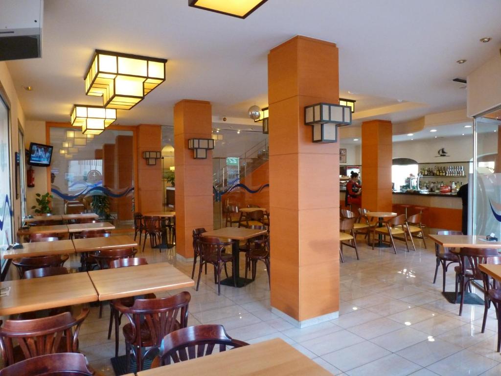 a restaurant with wooden tables and chairs and lights at Hotel Costa Brava in Blanes