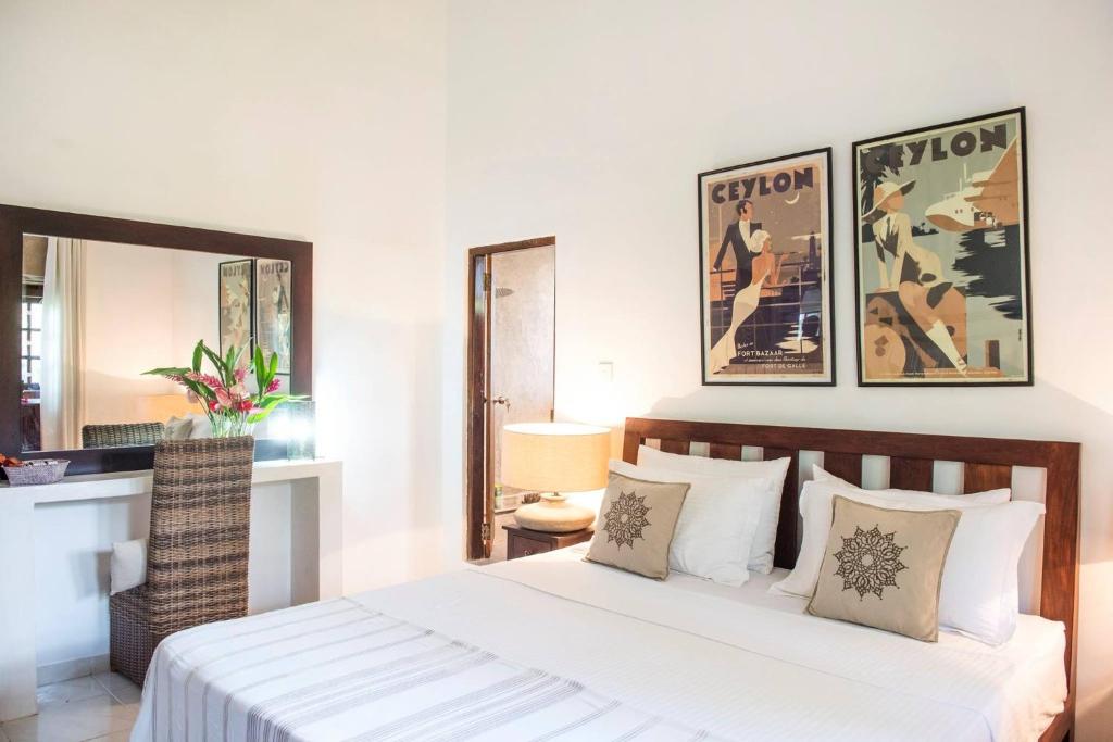 a bedroom with a bed and a desk and a mirror at Temple House Villa in Hikkaduwa