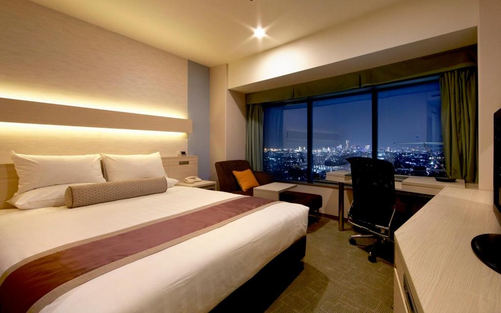 a hotel room with a bed and a desk and a window at Shin Yokohama Prince Hotel in Yokohama